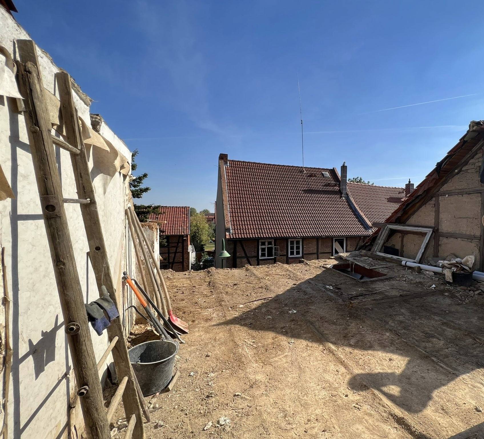 Beräumte, ebene Fläche nach dem Abbruch, links die Wand des Nachbarhauses mit Leiter und Werkzeug