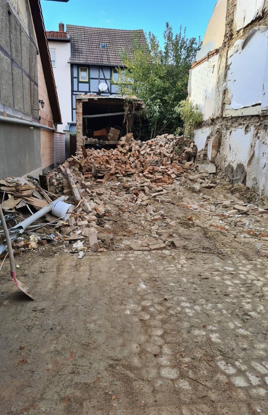 Abbruchschutt aus Ziegeln und Holz zwischen zwei Nachbarhäusern in einer engen Gasse