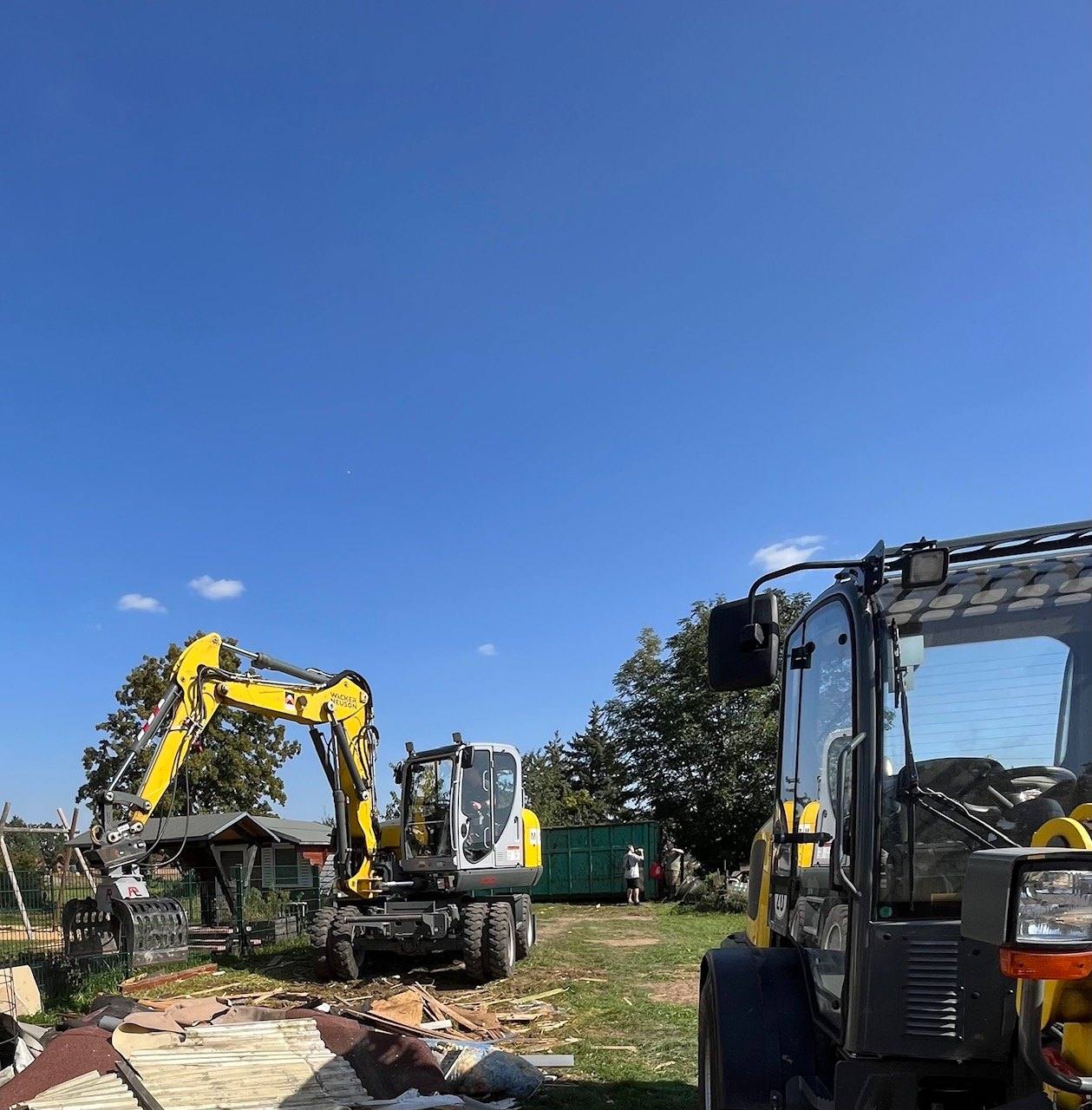 Bagger, Radlader und Container auf einer Wiese bei der Beräumung eines Grundstücks