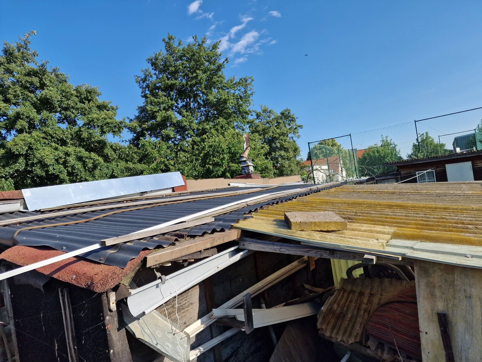 Schuppen mit eingesunkenem Wellplattendach und Holzresten