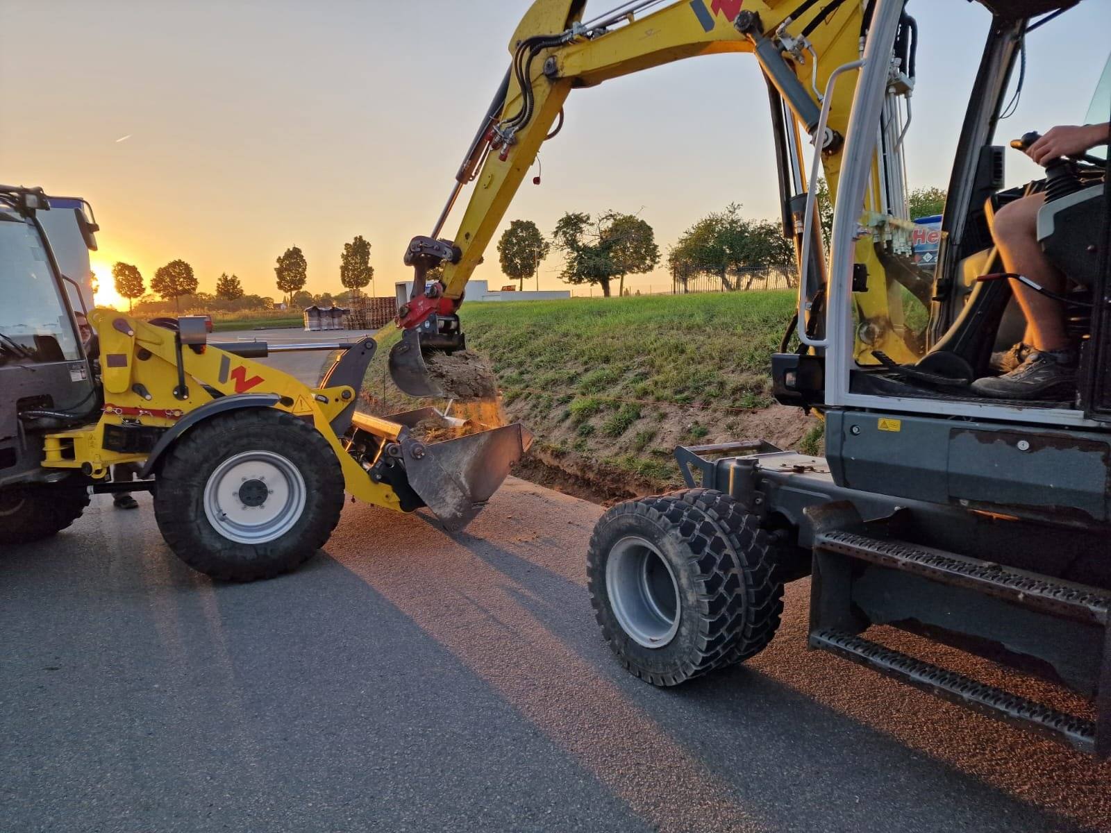 Radlader und Mobilbagger am Straßenrand im Abendlicht