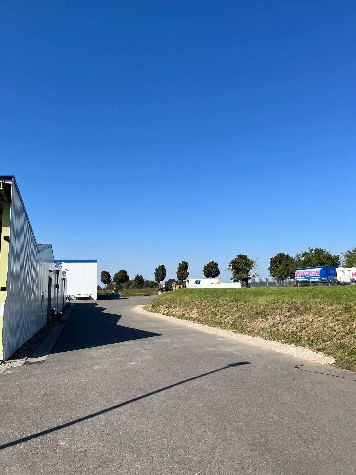 Gewerbestraße mit Grünstreifen unter blauem Himmel