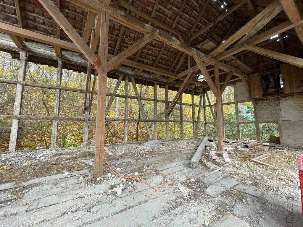 Innenraum der Scheune mit Holzstützen und Schutt auf dem Betonboden