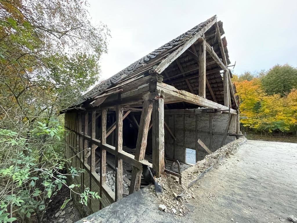 Offene Fachwerkscheune auf einer Betonplatte vor Herbstwald