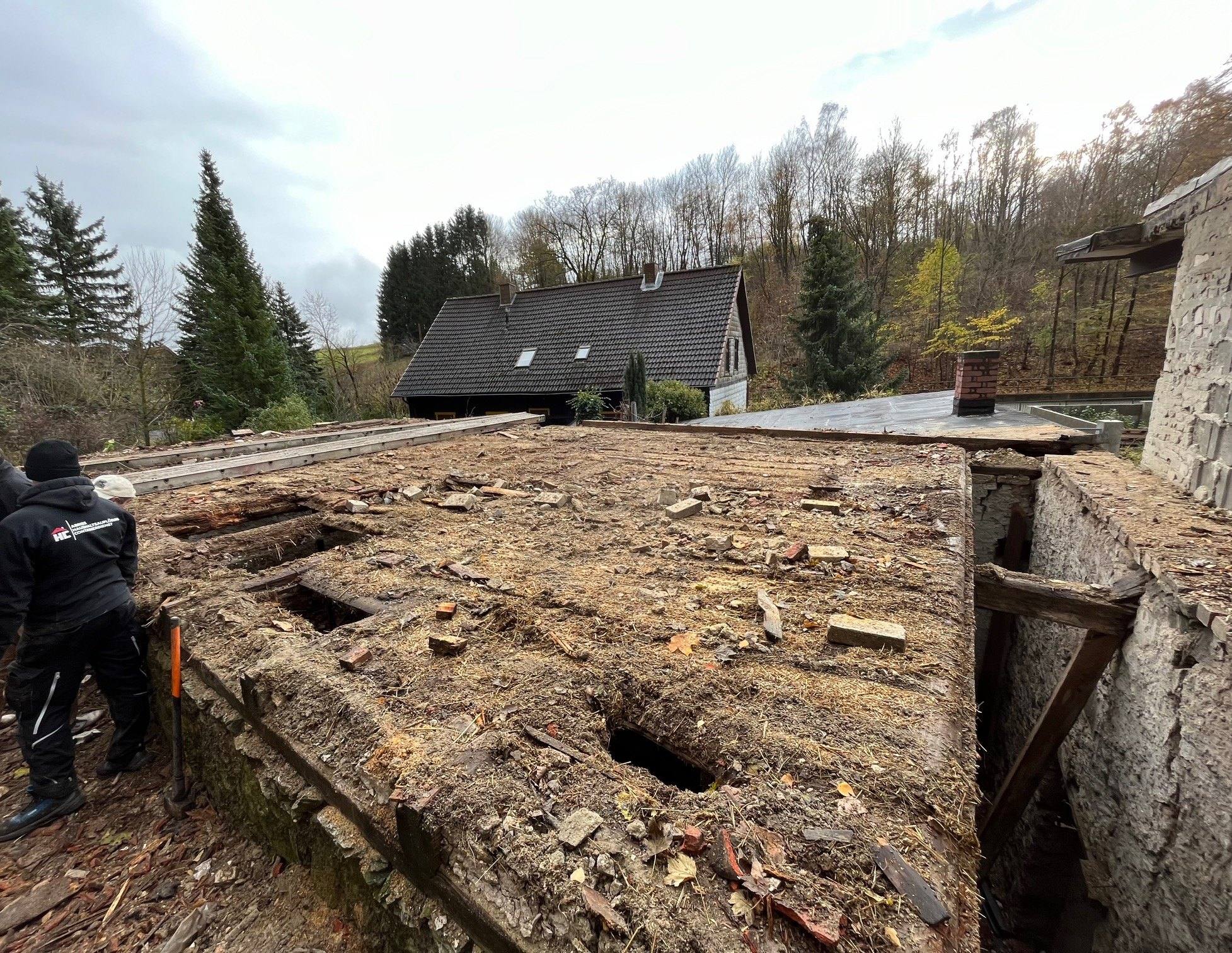 Mitarbeiter auf der Mauerkrone nimmt die Dachbretter des Nebengebäudes ab