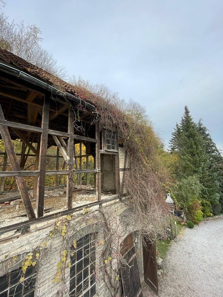 Mit Efeu bewachsenes Nebengebäude aus Bruchstein mit Fachwerk-Obergeschoss und Bogenfenstern