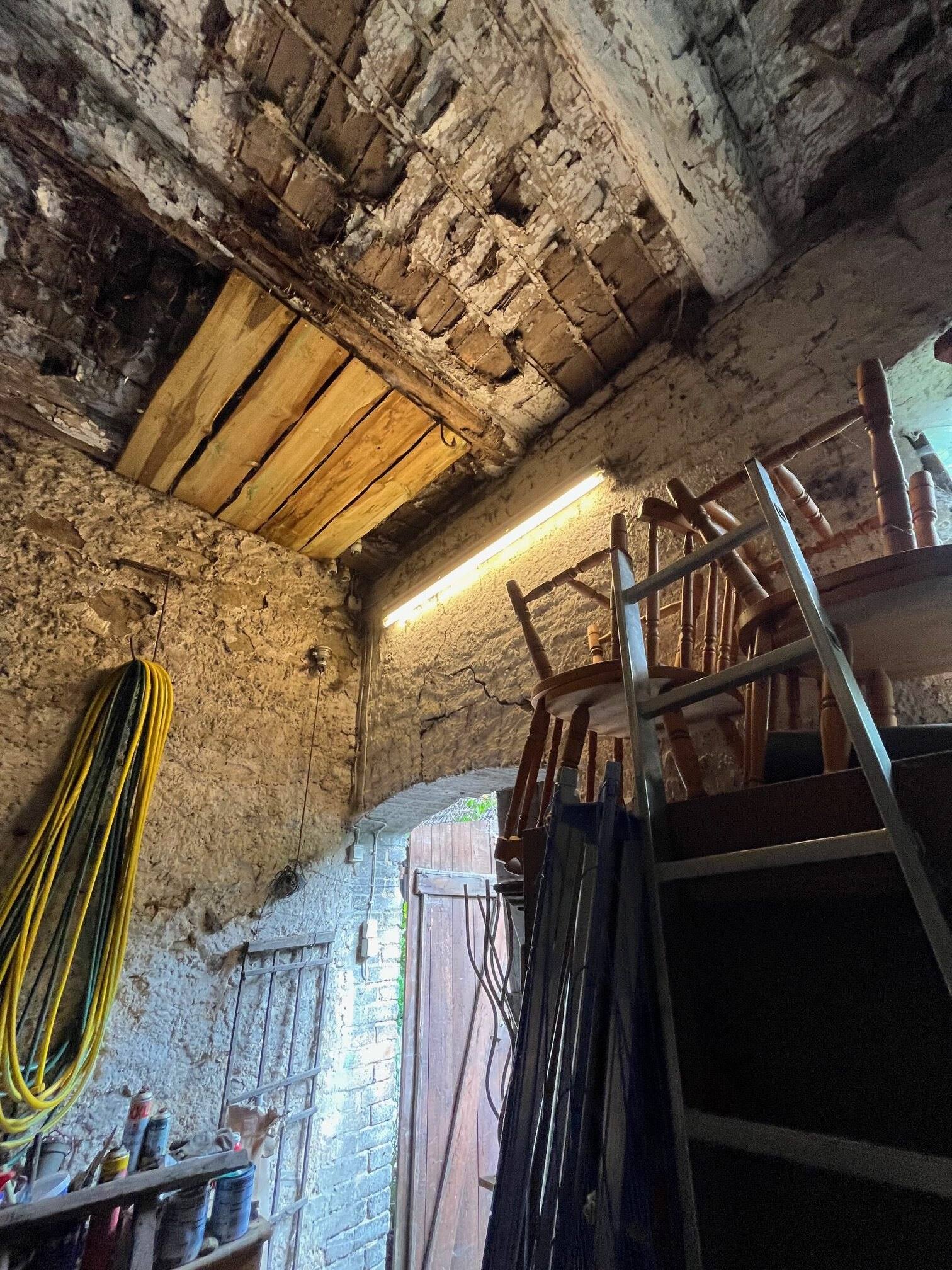 Abstellraum mit Leitern, Kabeln und Brettern unter einer alten Holzdecke