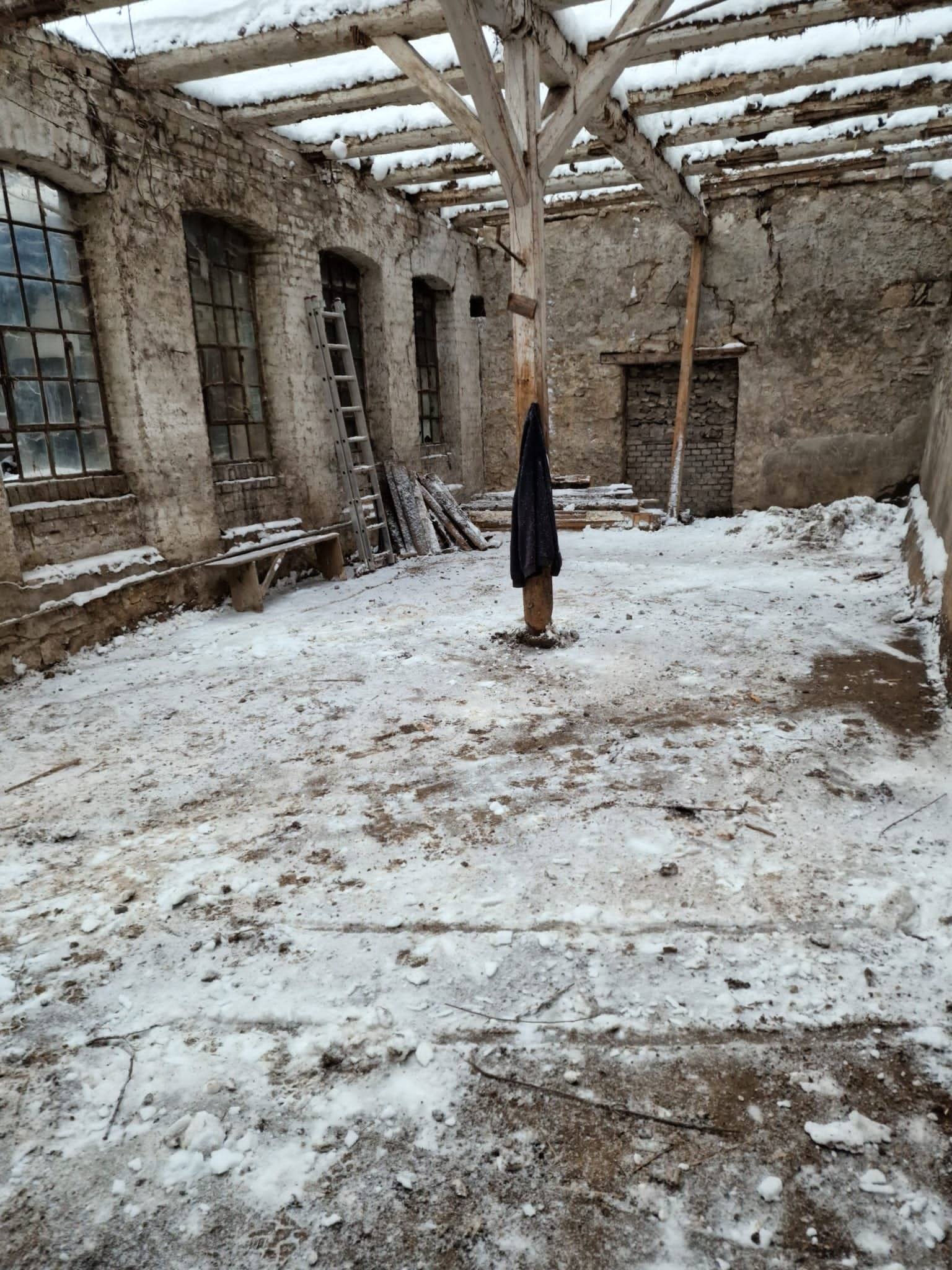 Leerer Innenraum des Nebengebäudes mit Schnee, Dach abgenommen, Bogenfenster in der Bruchsteinwand